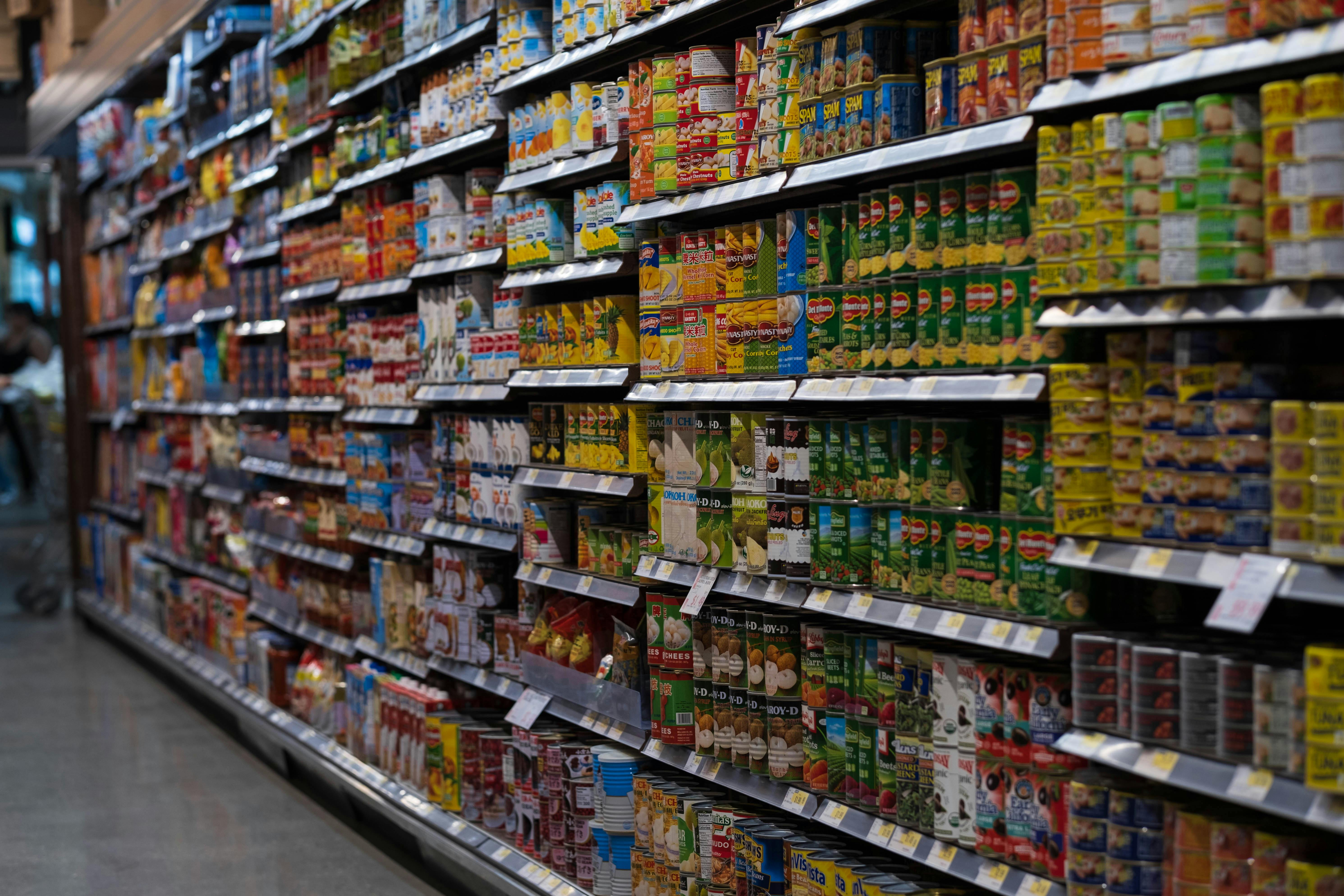 Pasillo de supermercado con latas y productos acomodados en estantes